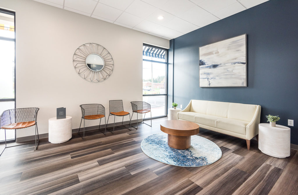 Modern dental waiting room with upholstered seating, accent wall, and contemporary décor