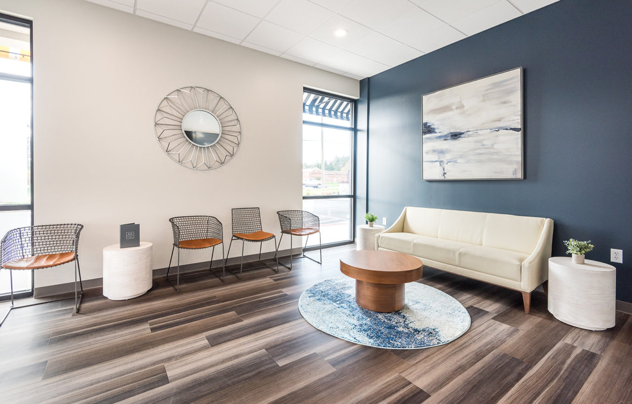 Modern dental waiting room with upholstered seating, accent wall, and contemporary décor
