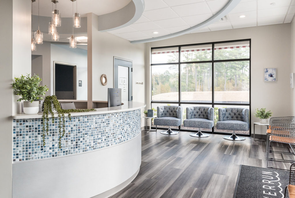 Welcoming dental office reception area with curved front desk and comfortable waiting room seating