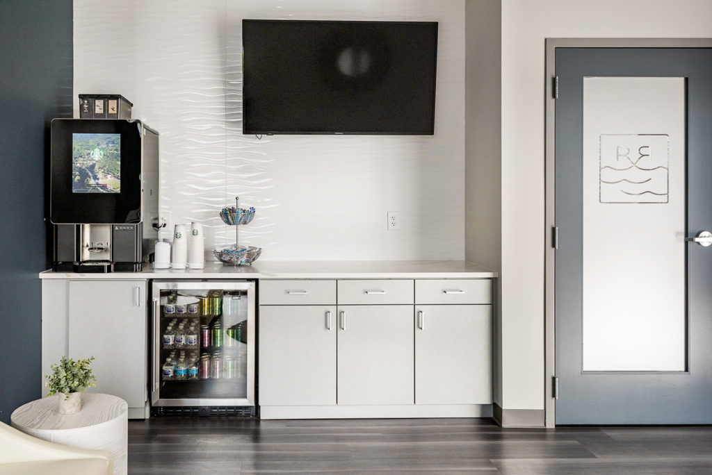 Dental office refreshment station with cabinetry, beverage machine, and wall-mounted television