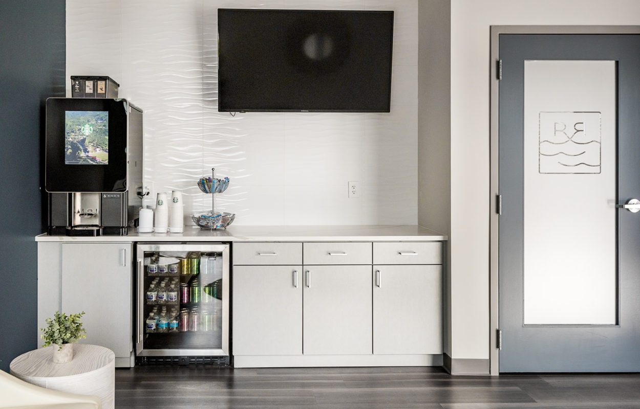 Dental office refreshment station with cabinetry, beverage machine, and wall-mounted television