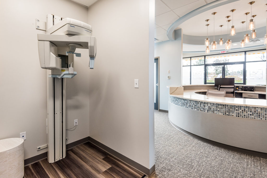 Digital panoramic dental X-ray machine positioned in a clean, modern dental office hallway
