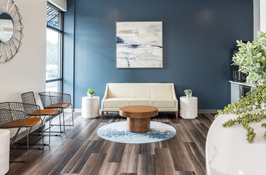 Spacious dental office lounge area featuring blue accent walls, seating, and natural light